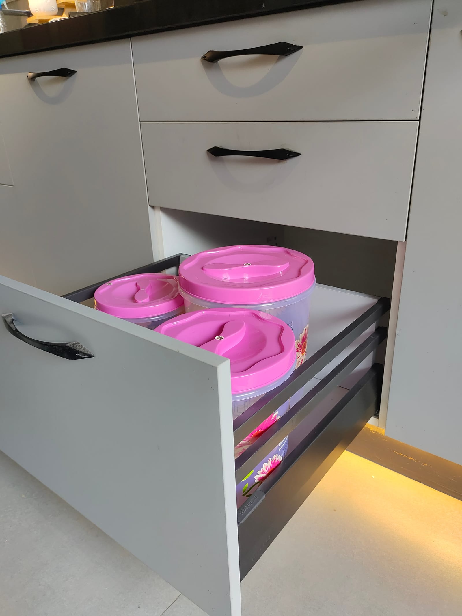 A steel-sided drawer box open in a white kitchen, with the Häfele name visible on the runner