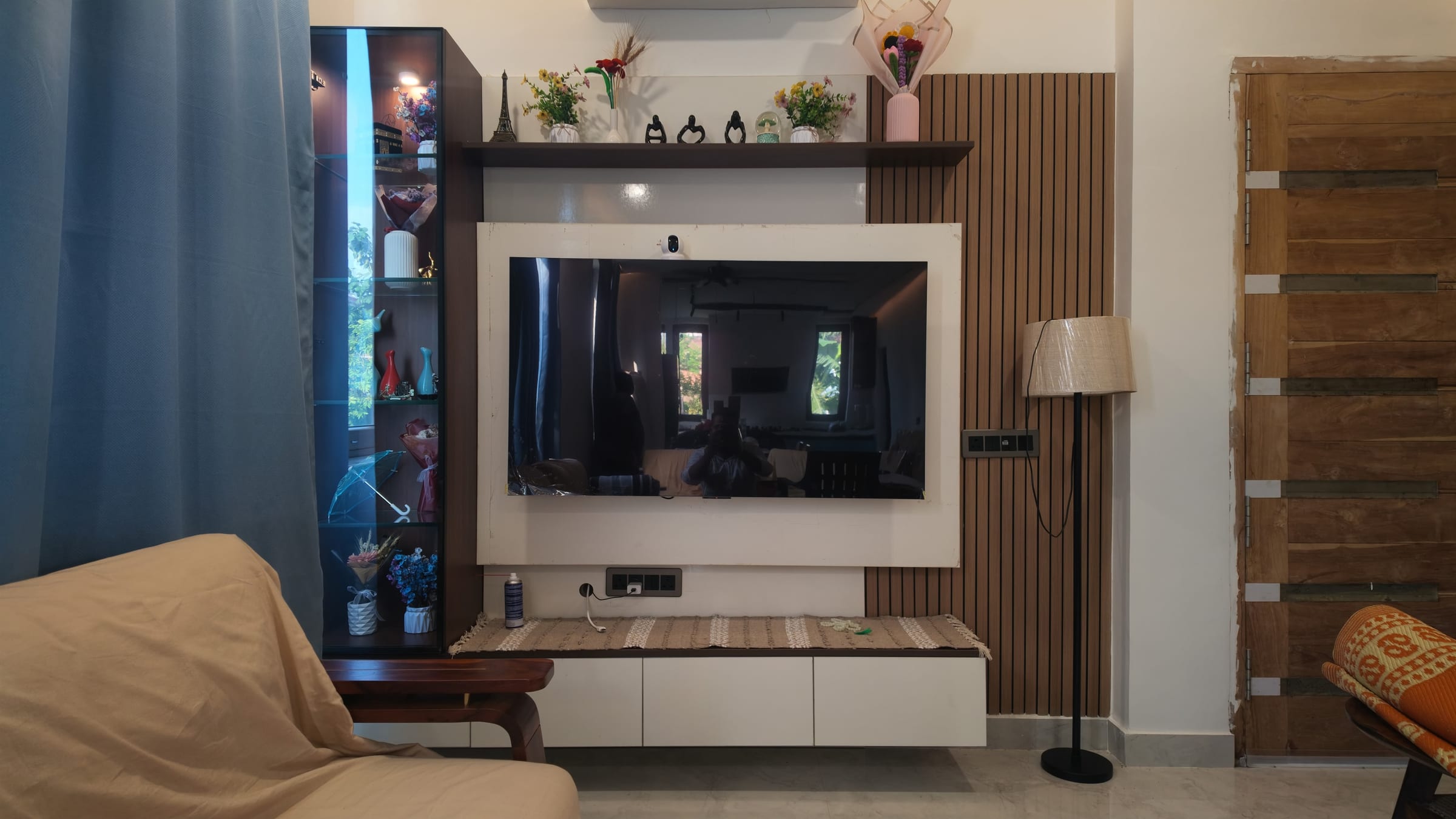 The finished television wall, a white panel surrounded by fluted wood with a glazed display column at one end and floating drawers below