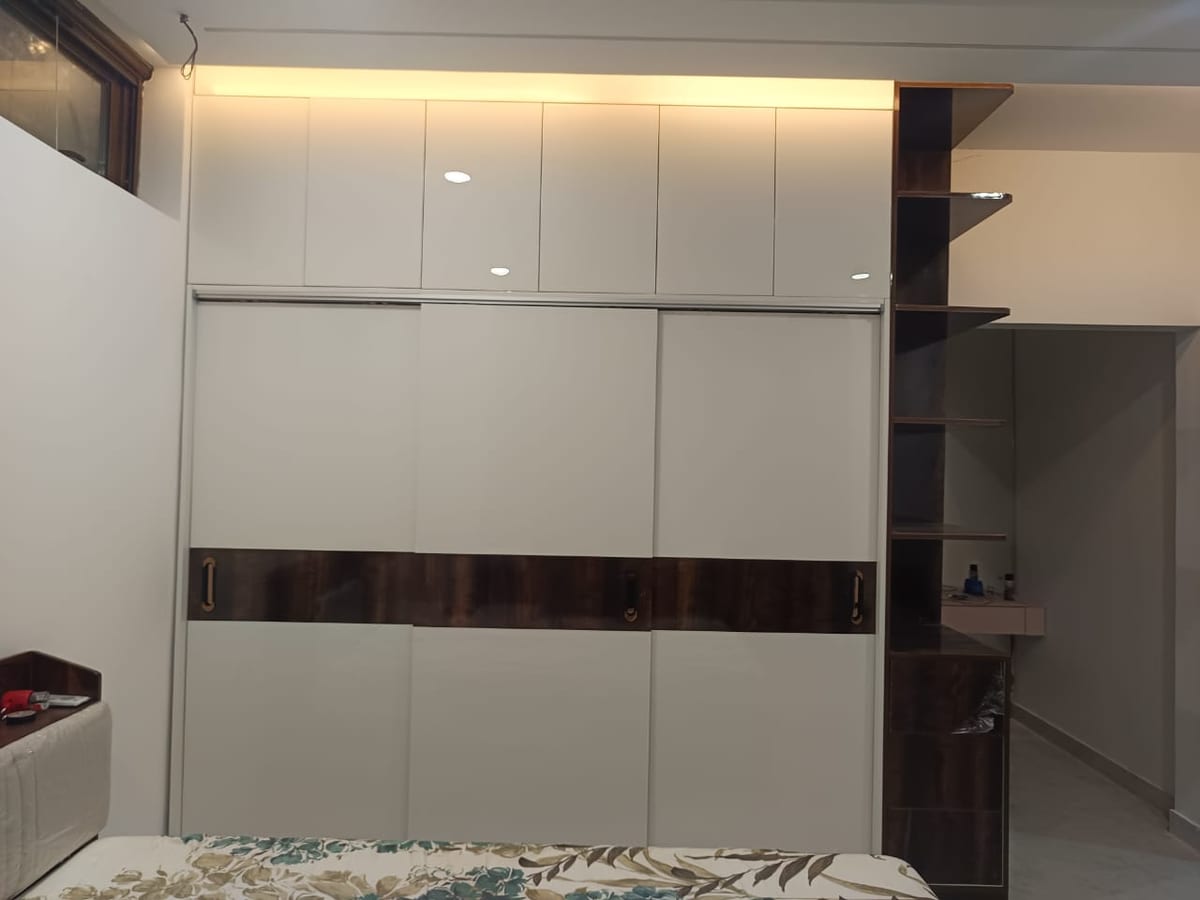 A white sliding wardrobe with a wood band and open shelving